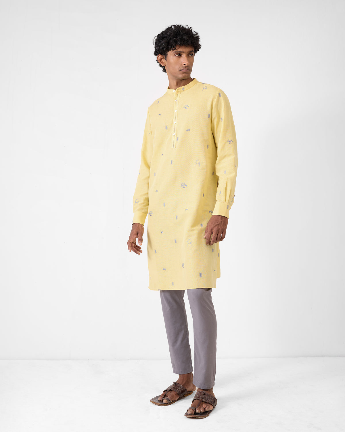 Person wearing a light yellow Astral kurta with grey embroidery.