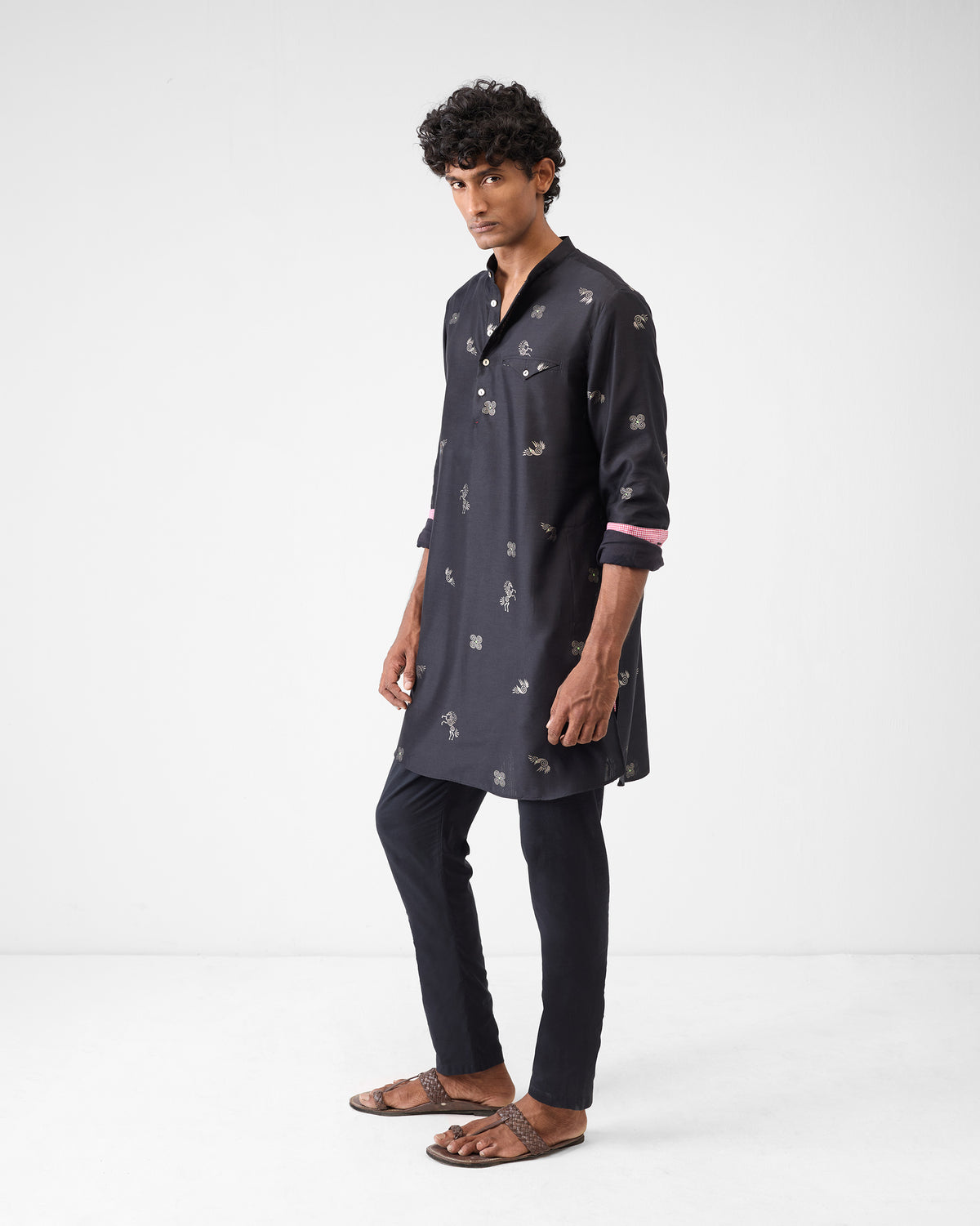 Three-quarter view of a black Fort Kurta with silver foil print and pink cuffs.