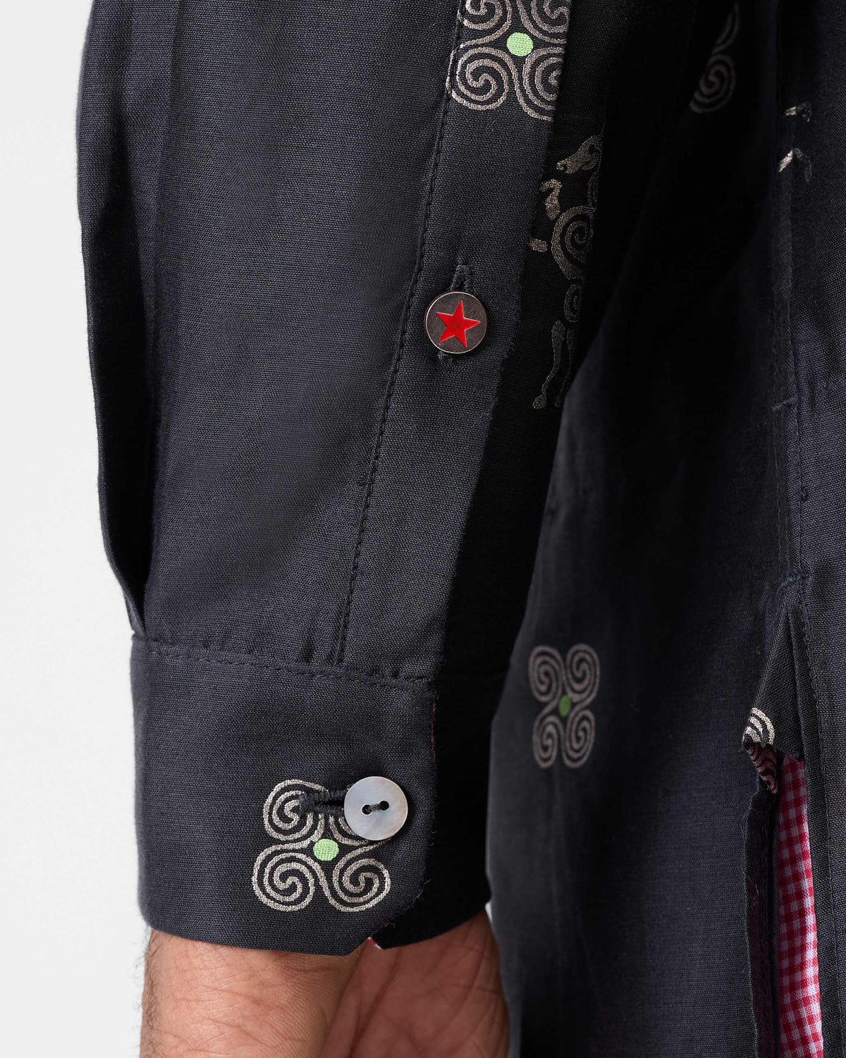 Close-up of a Fort Kurta cuff with silver foil motifs and a star button.