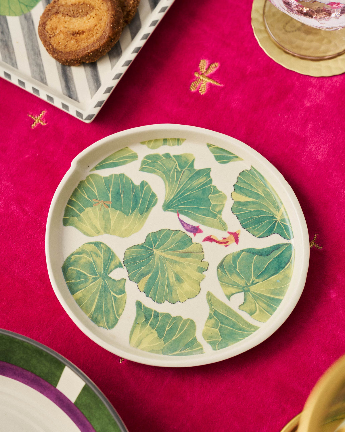 Lily Pond dessert plate with lily pads and fish on a pink tablecloth.
