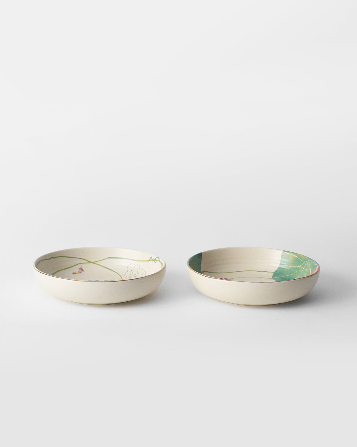 Pair of ivory Lotus Garden shallow bowls with gold rims.