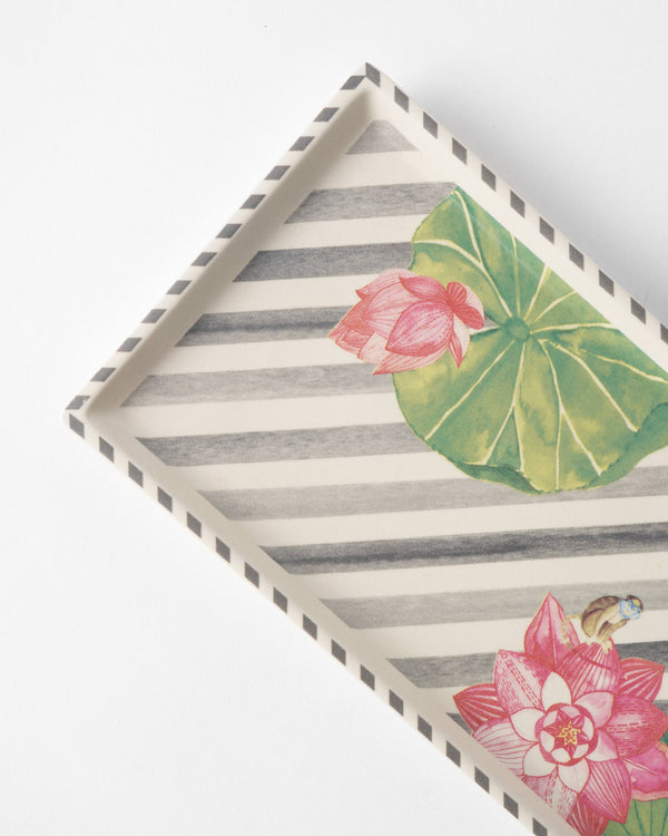 Close view of a pink lotus and a green lily pad over charcoal stripes