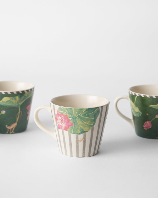 A striped mug with a pink lotus on a lily pad between two green mugs