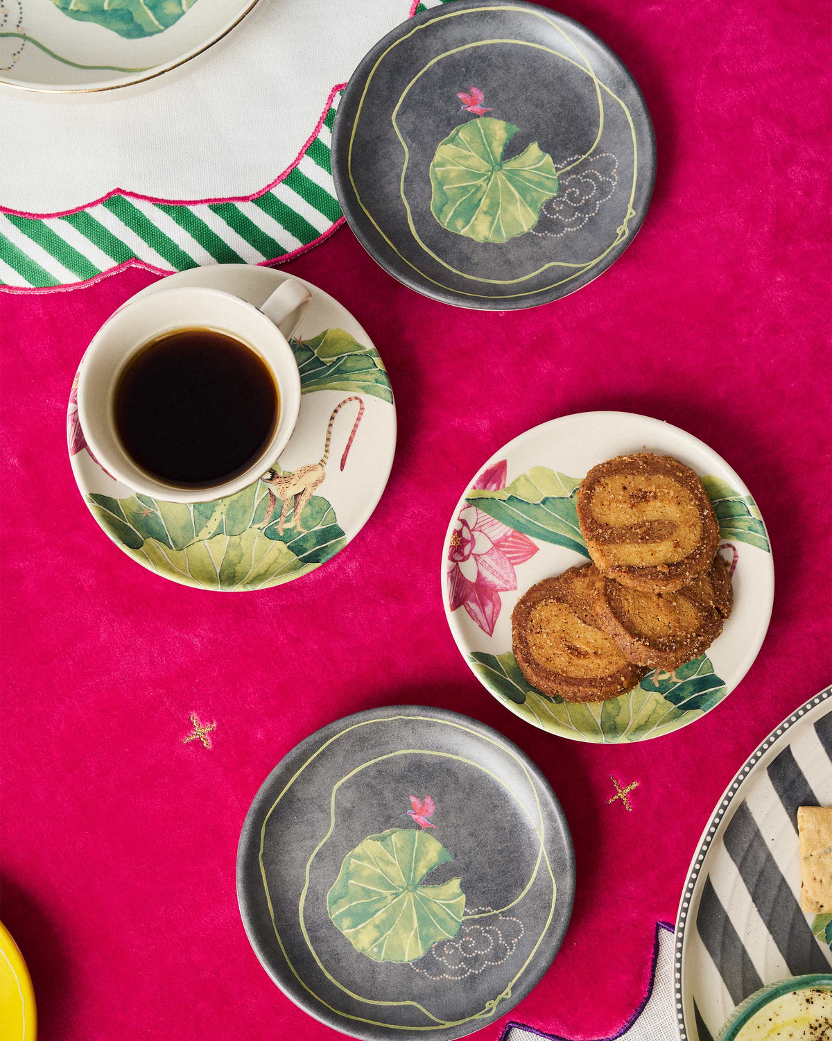 Float tea plates with coffee and biscuits on a pink table.