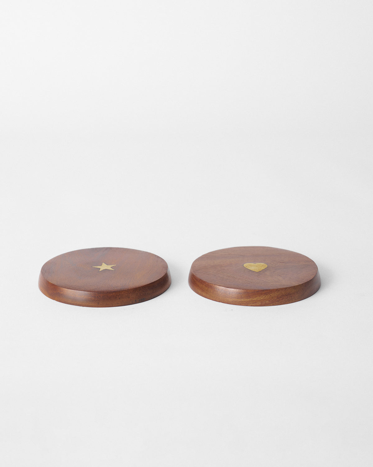 Two thick wooden Aster mug lids with a brass star and a brass heart.
