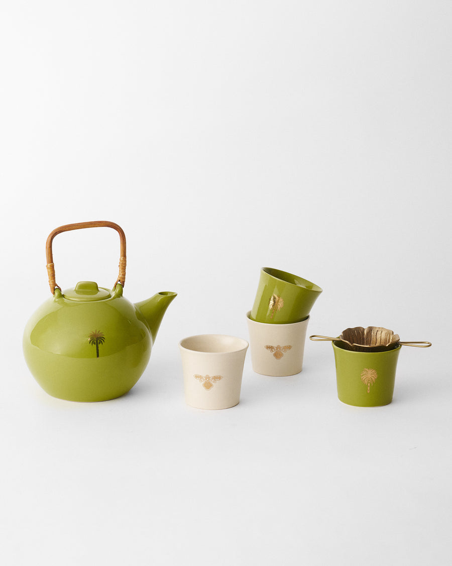 An olive teapot with a bamboo handle, four cups and a flower-shaped brass strainer