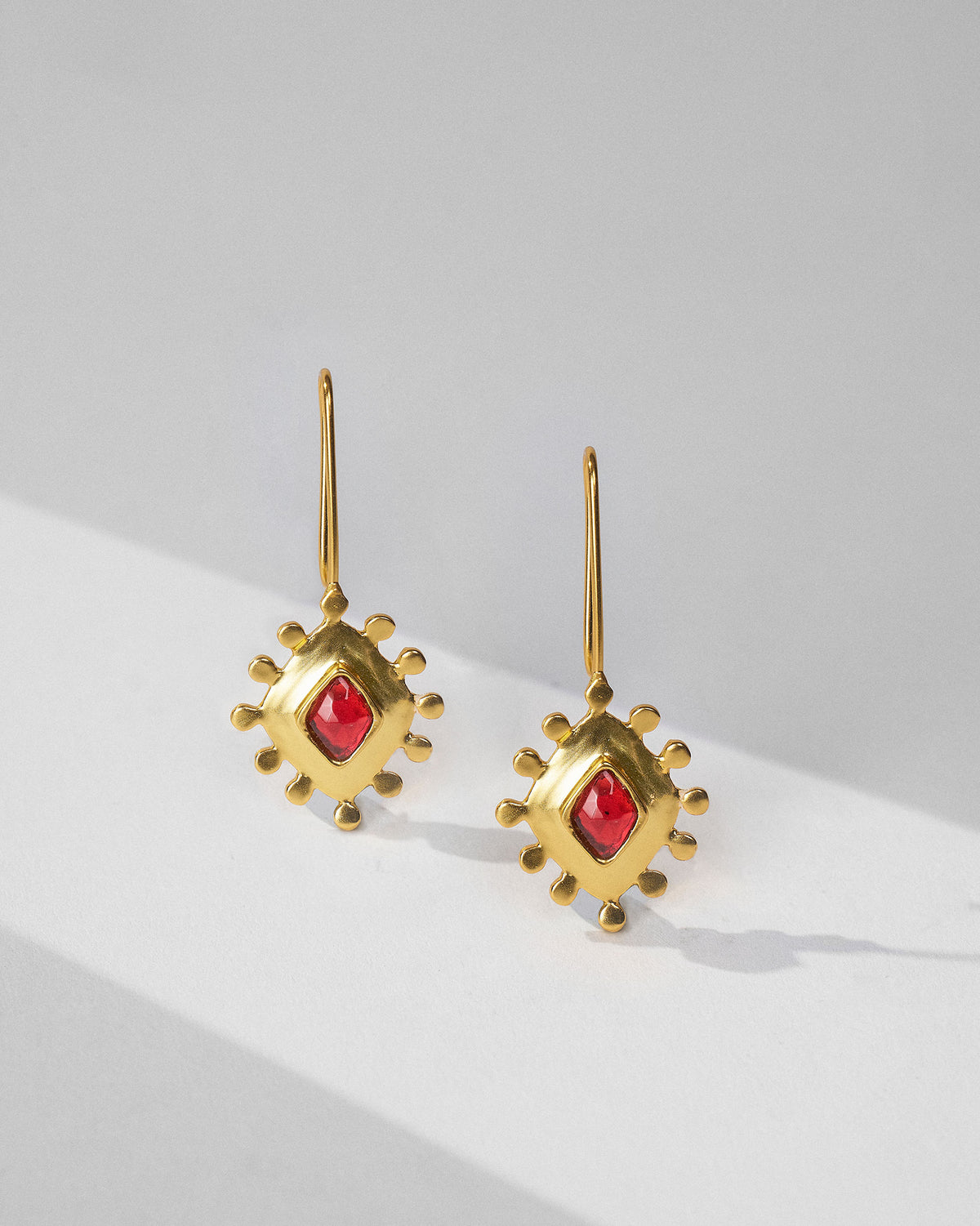Gold garnet barfi drops hanging from long hooks.