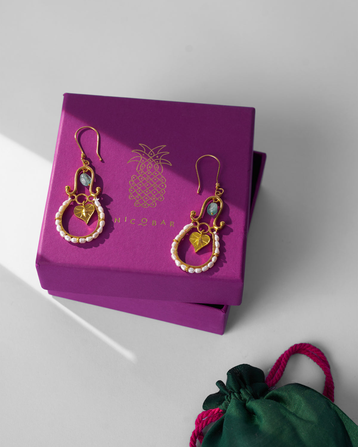 Gold Peepal Patta danglers on a purple Nicobar gift box.