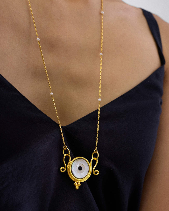 Gold Turki Nazar chain with an eye pendant worn at the chest.