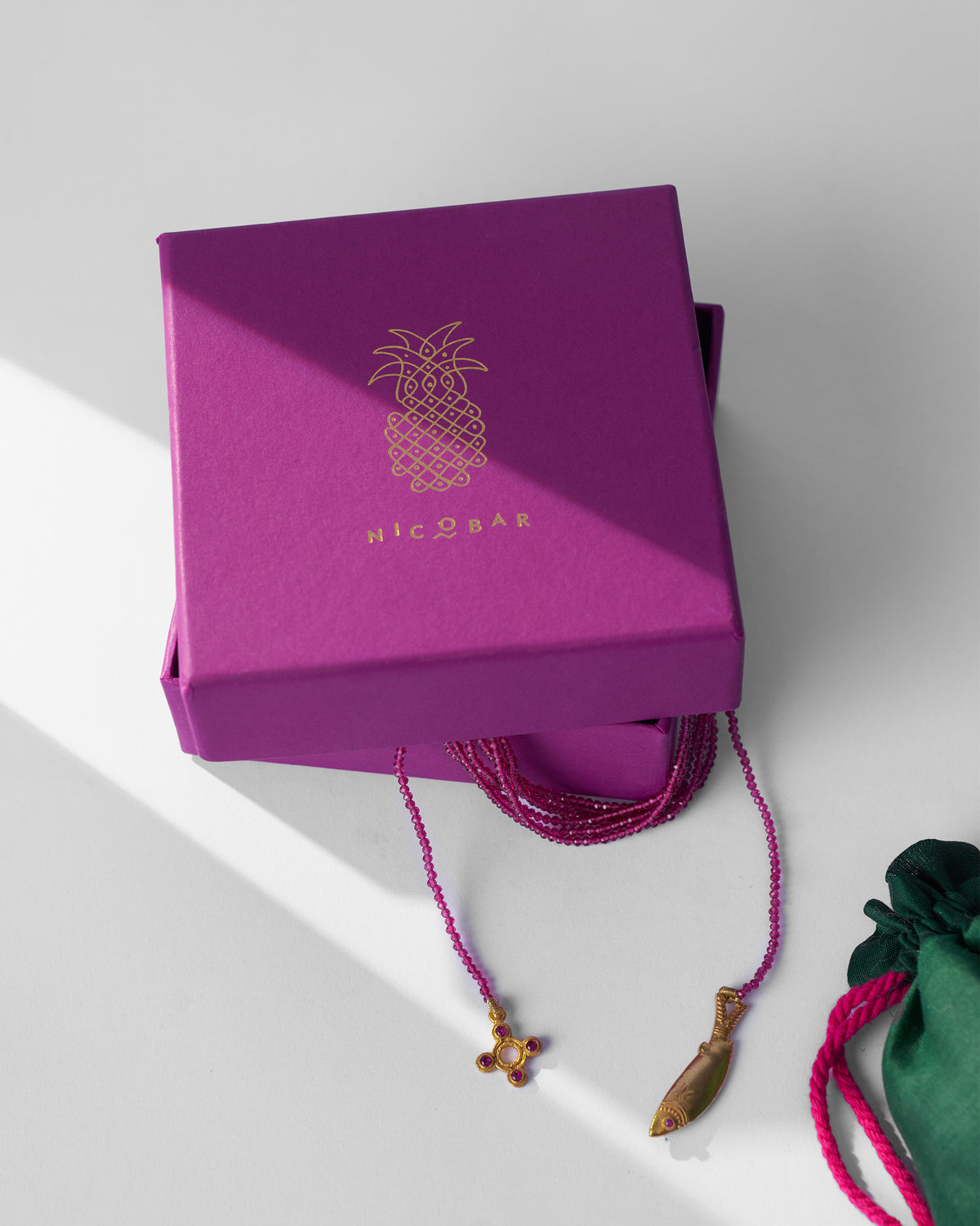 Jal Pari magenta bead necklace spilling from a magenta Nicobar jewellery box.