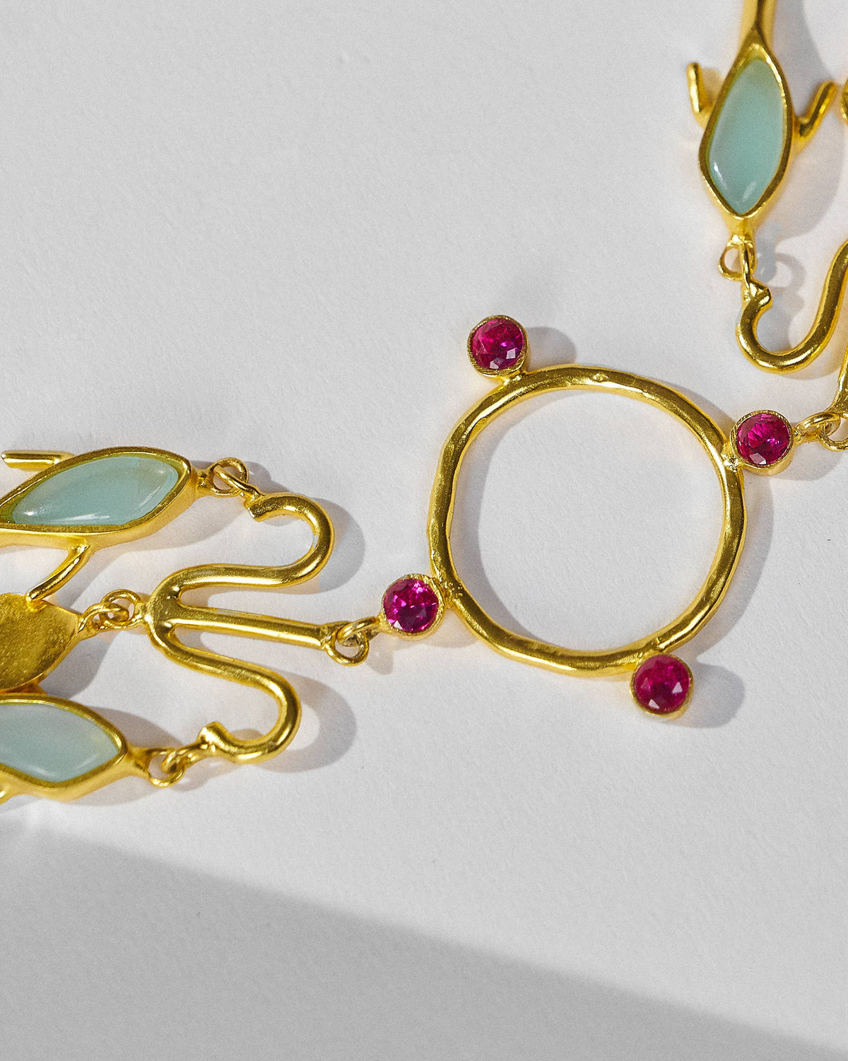 Close-up of the Indus necklace centre hoop with pink and pale green stones.