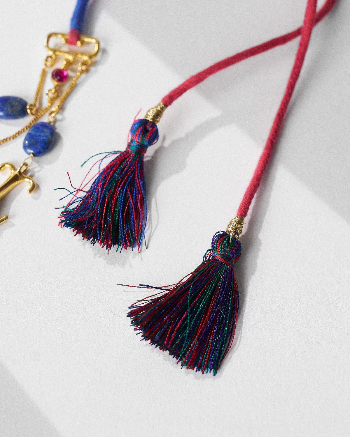 Close-up of fuchsia cords ending in multicolour tassels on the Indus necklace.