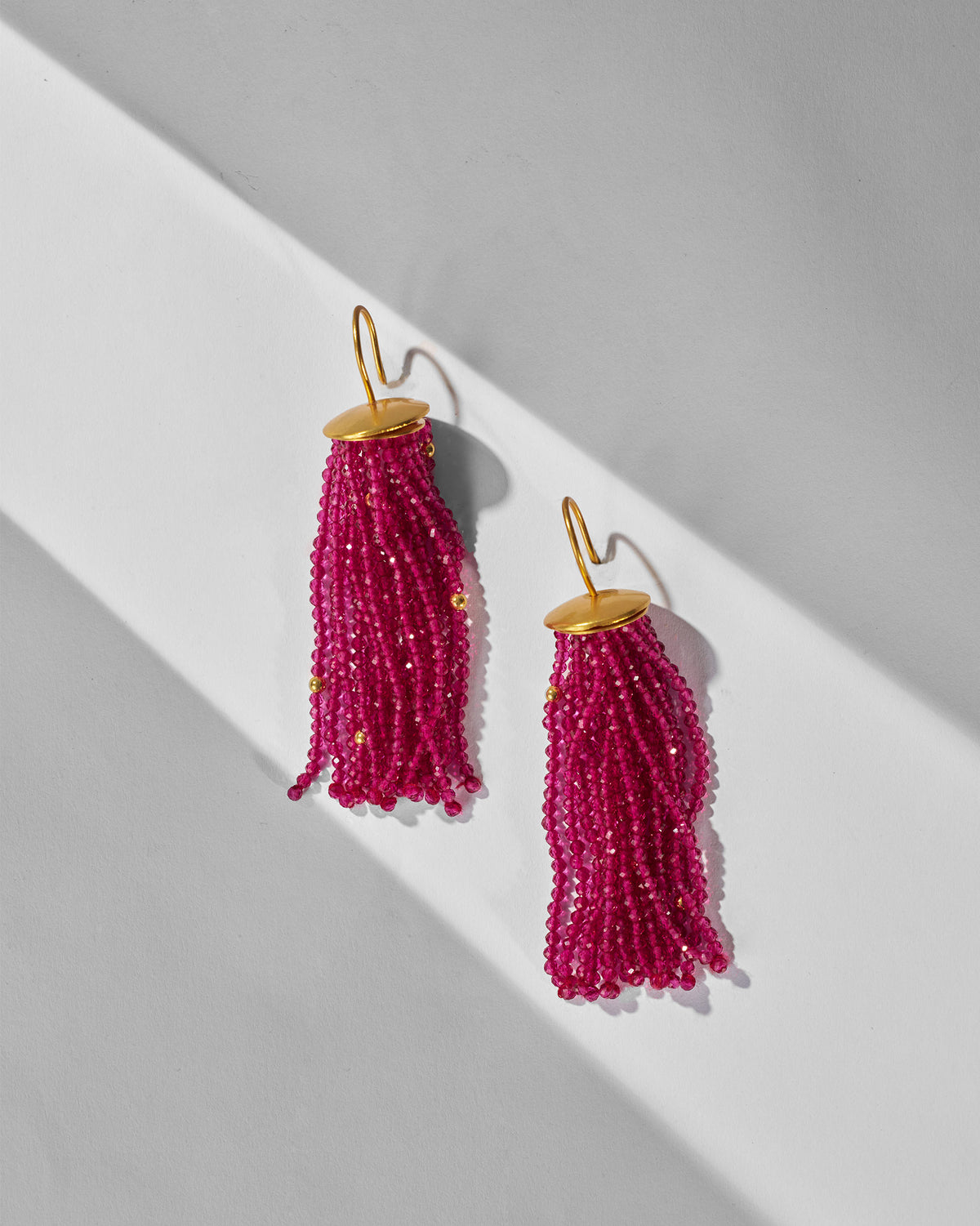 Pair of magenta Glass Tassel earrings laid flat showing multi-strand beads.