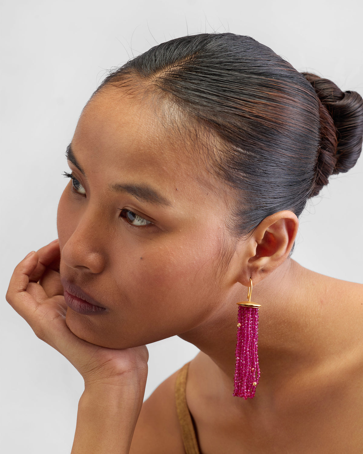 Side view of a magenta Glass Tassel earring hanging beside a person's face.