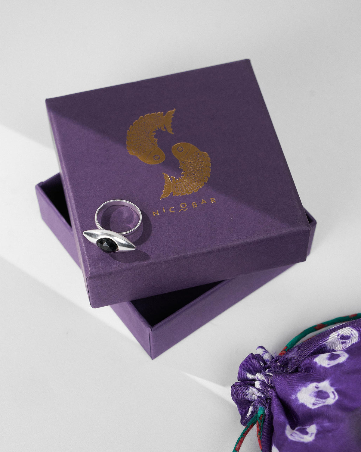 Silver All Seeing Ring with black onyx on a purple Nicobar gift box.
