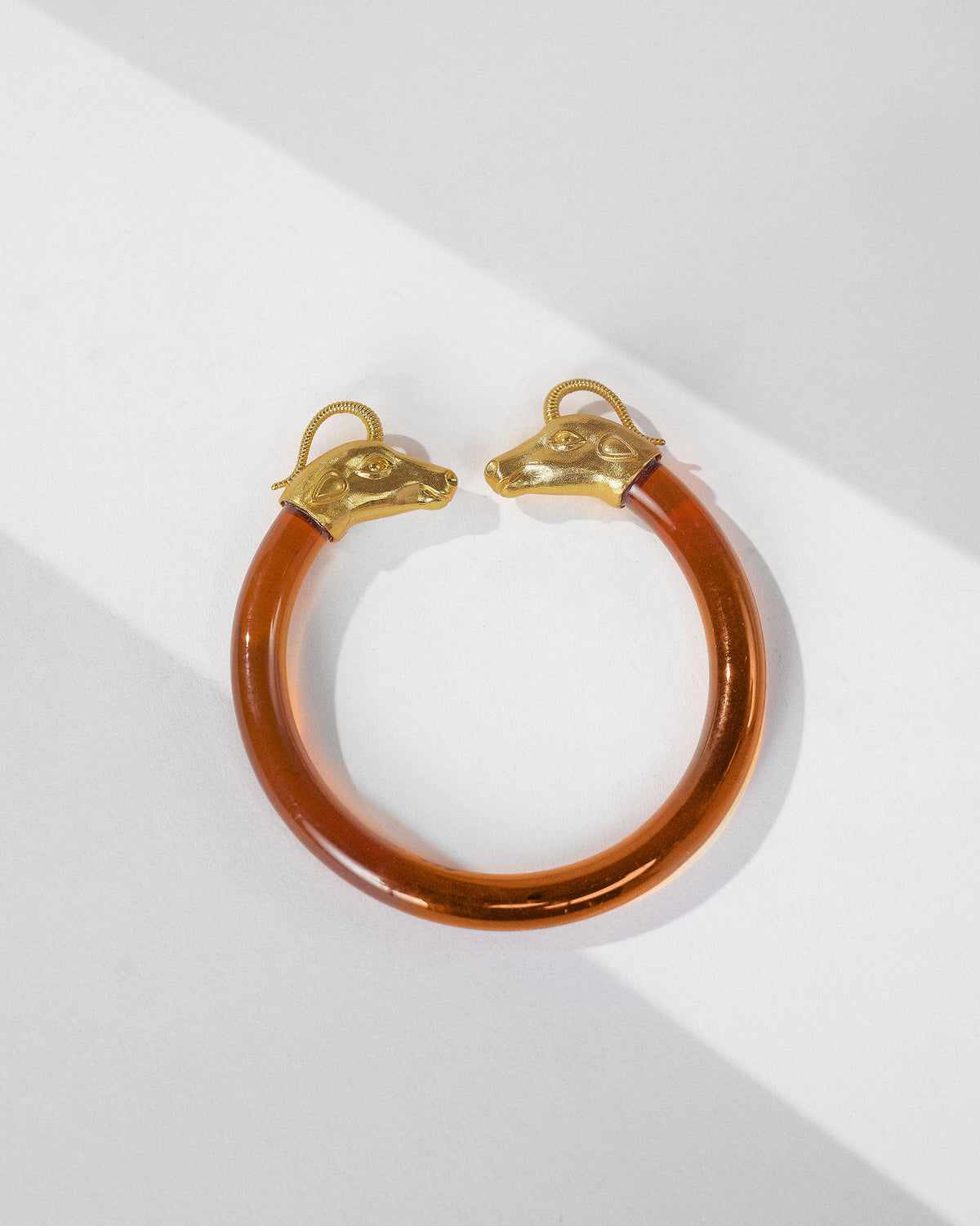 Amber Unicorn open bangle with gold animal-head ends laid flat.