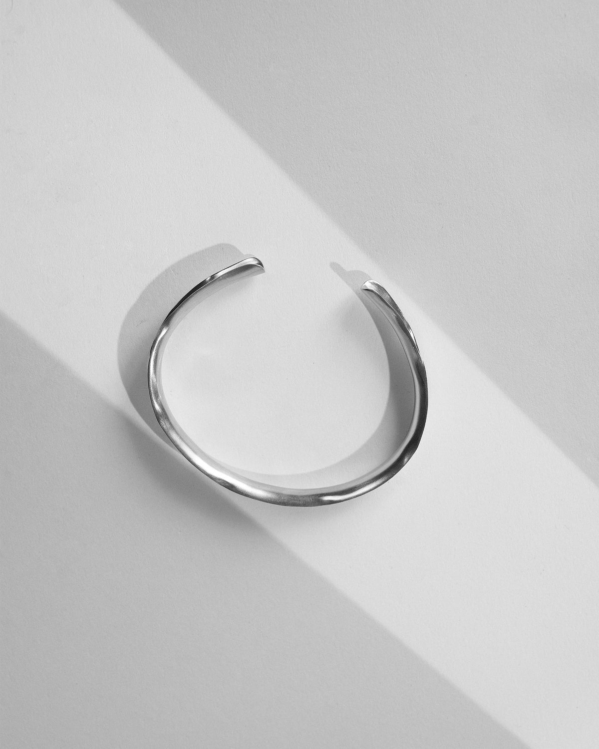 Thin silver Batur open cuff bangle laid flat.