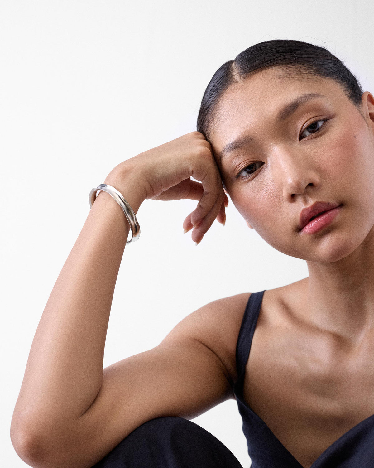Person wearing a thin silver Batur cuff bangle on the wrist.