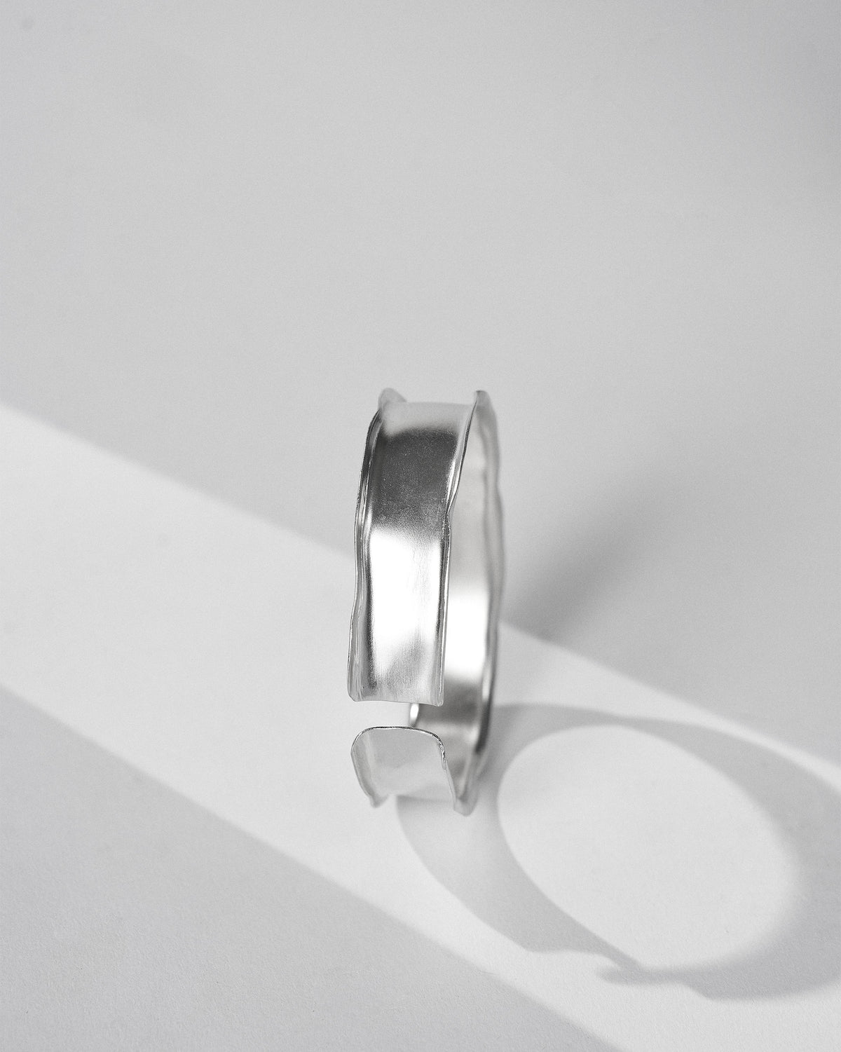 Side view of a thick silver Batur cuff with wavy raised edges.