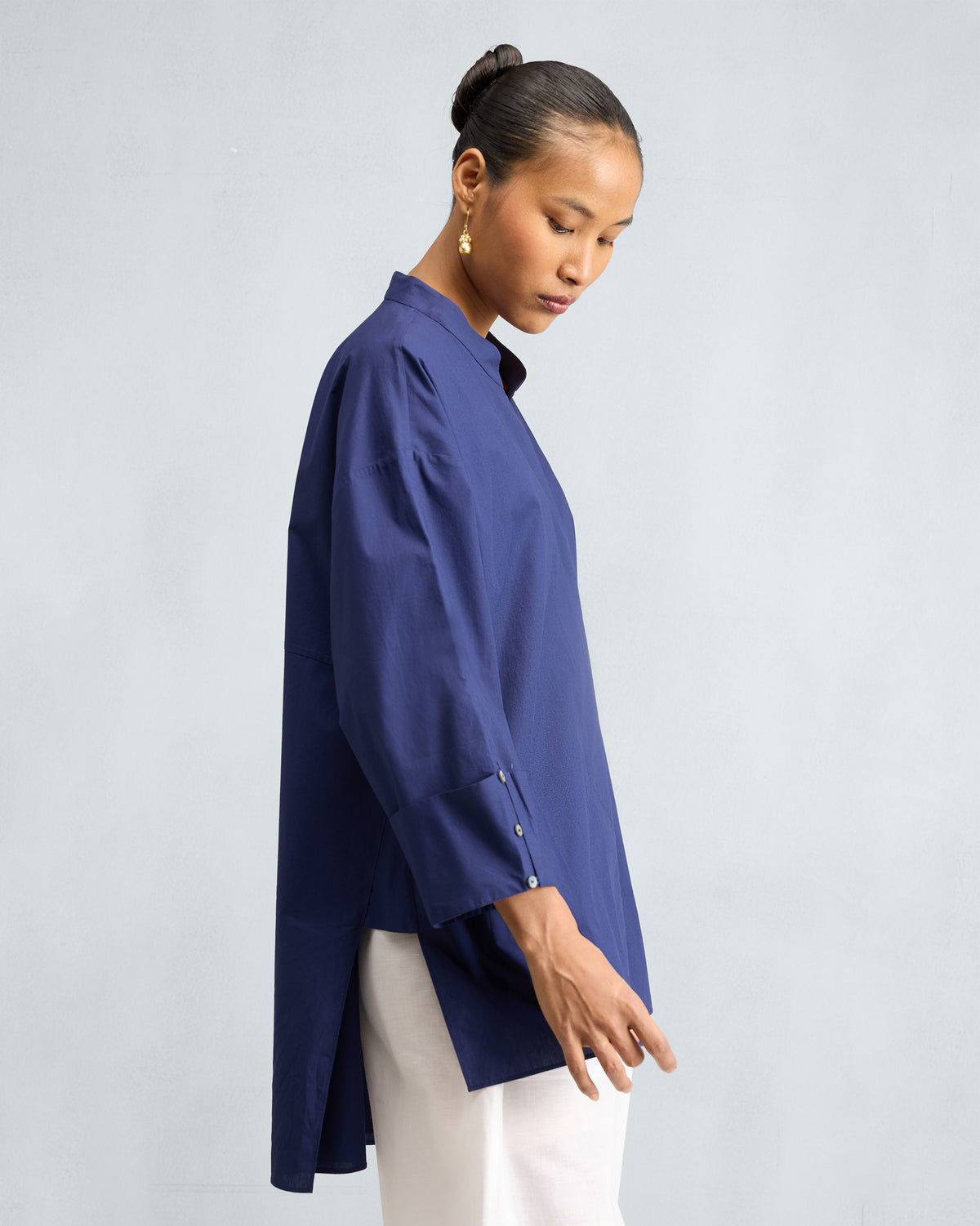 Side view of an ink blue Cirrus Shirt with a side slit hem.