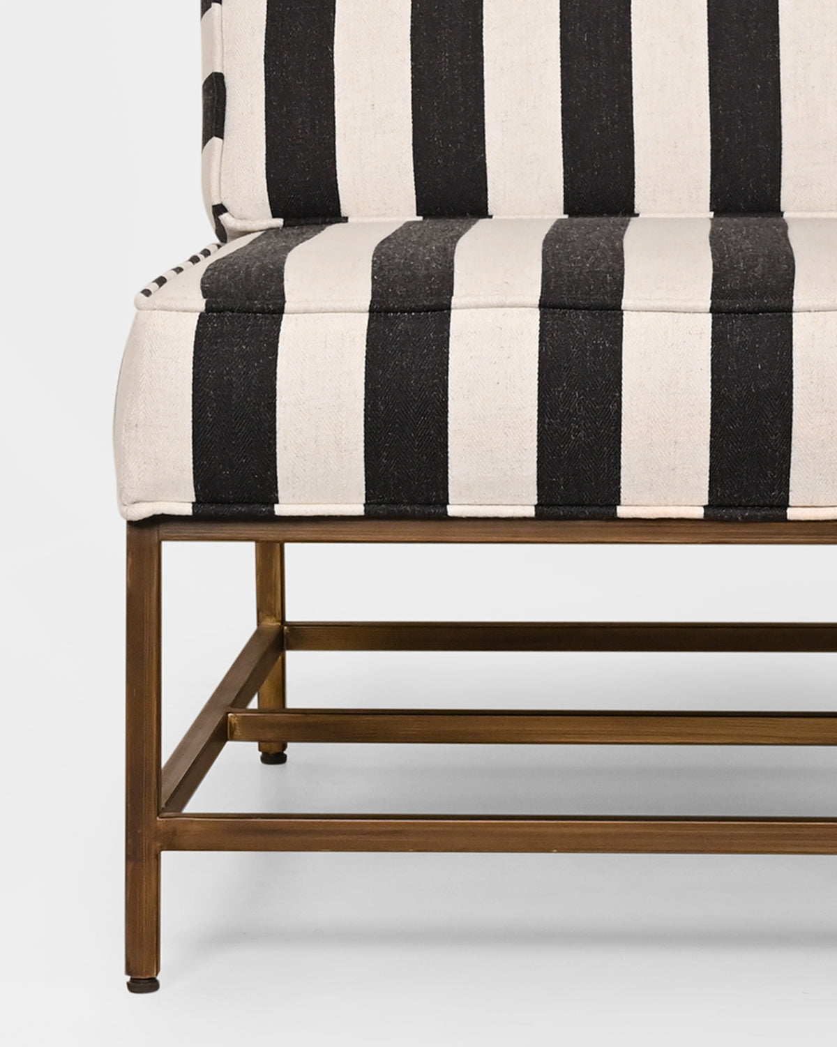 Close-up of Isle Chair showing its striped seat and brass-toned legs.