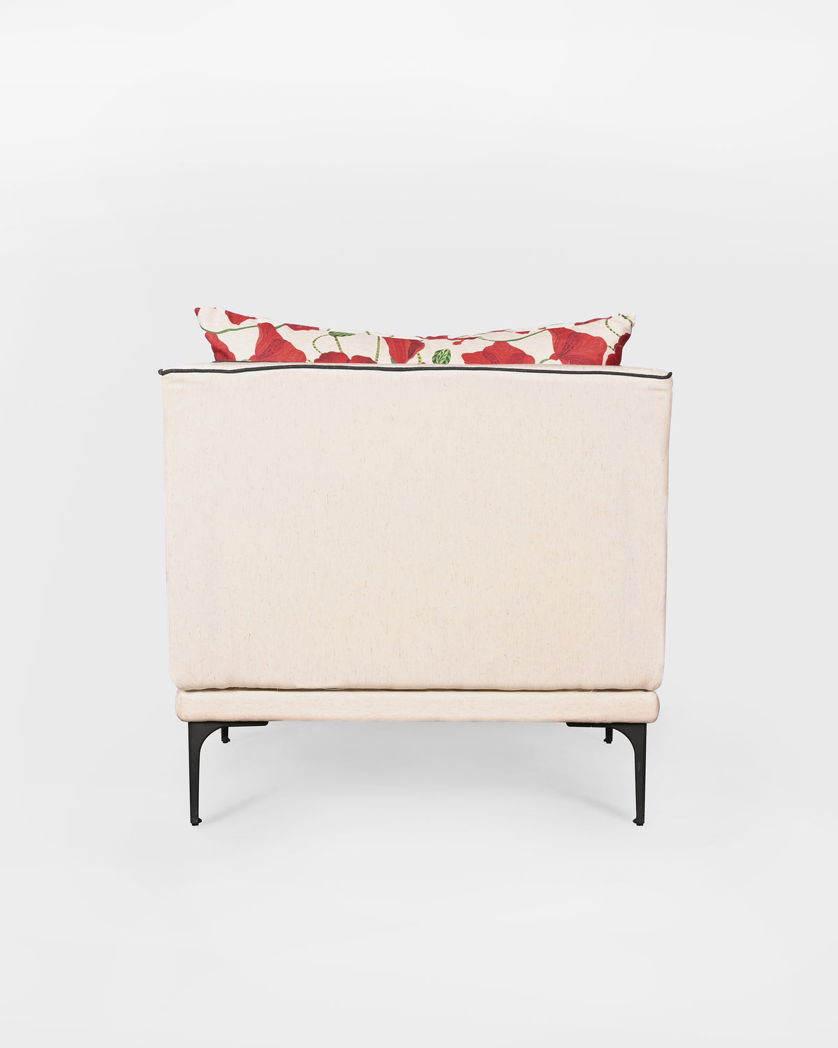 Back of a cream Field lounge chair with black piping and poppy cushion.