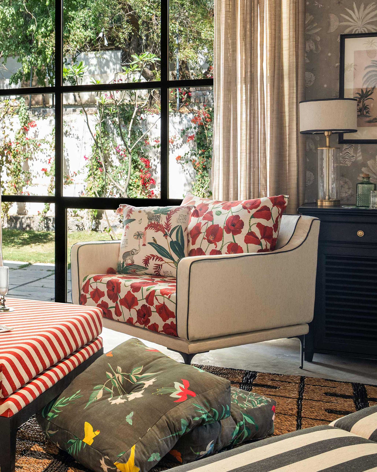 Field lounge chair with red poppy cushions styled by a garden window.