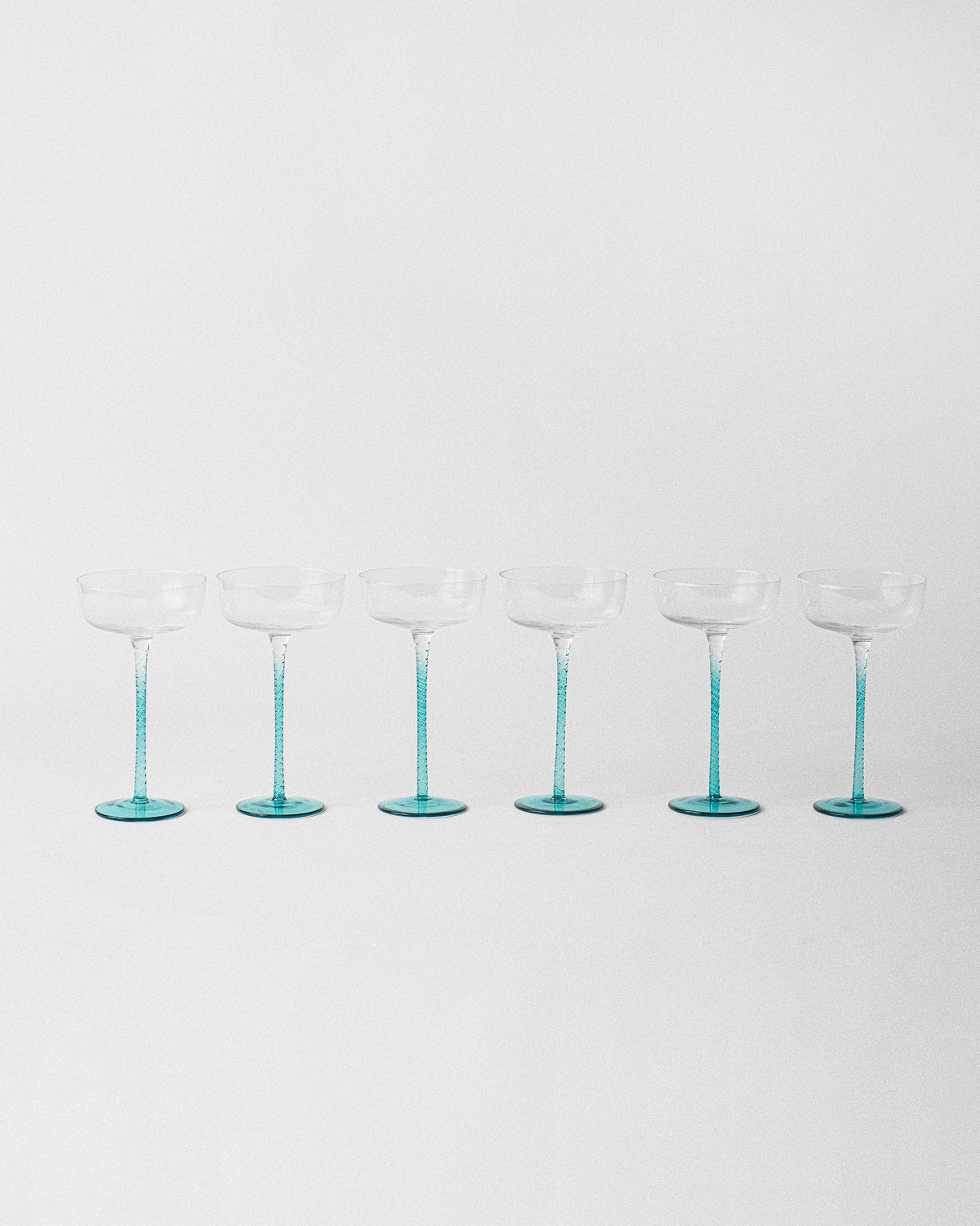 Set of six Lumen cocktail glasses with clear bowls and teal stems.