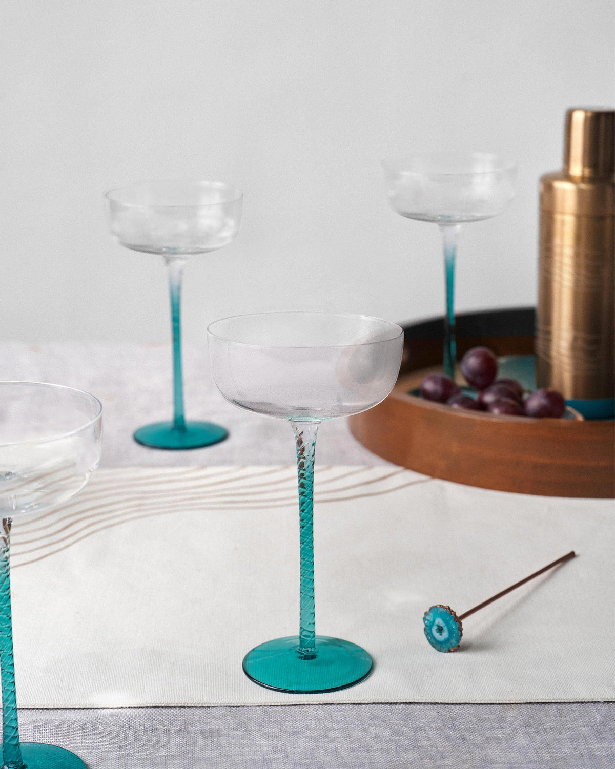 Lumen cocktail glasses with teal stems styled on a table for drinks.