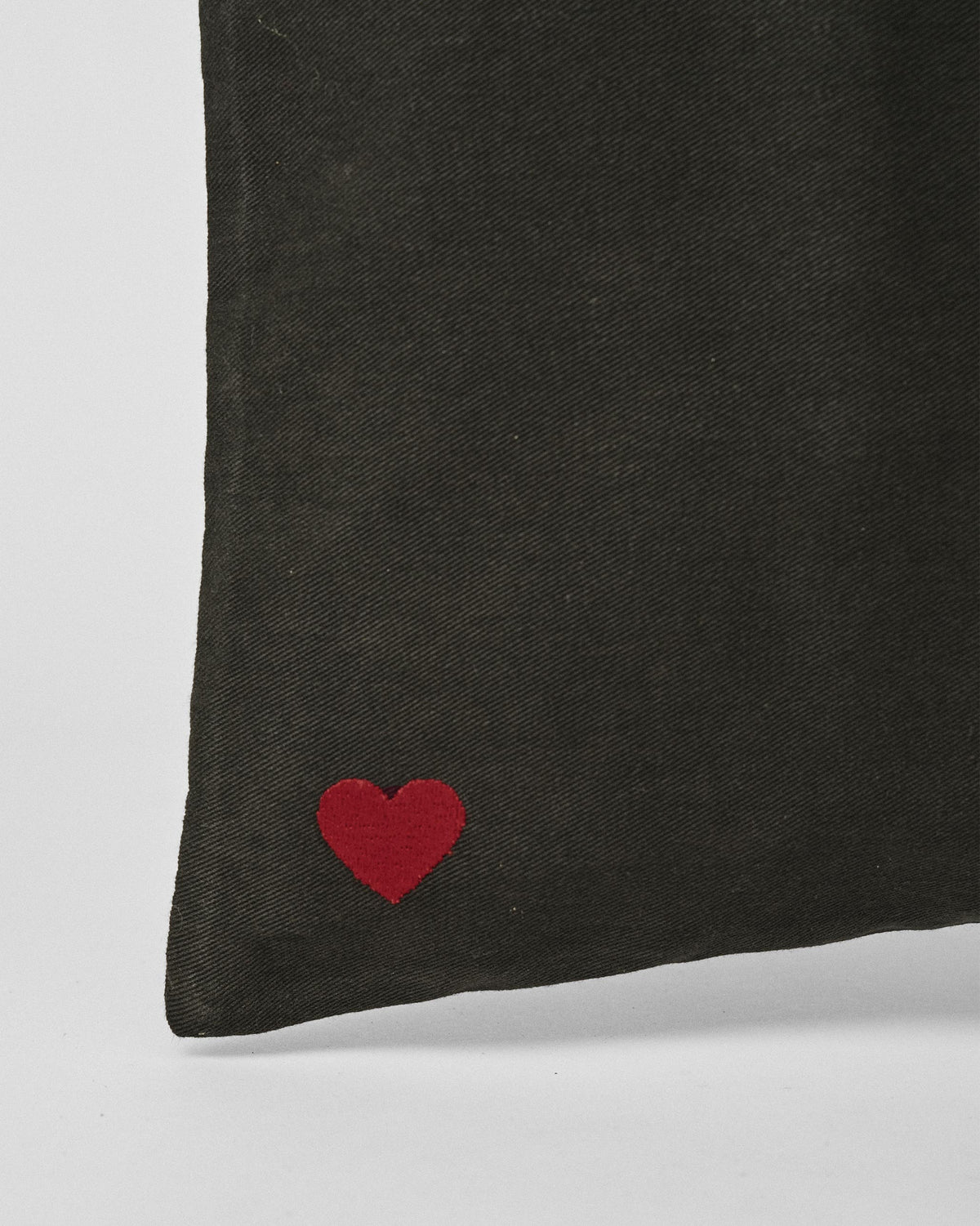 Close-up of a red heart embroidered on a charcoal Decade Tote.