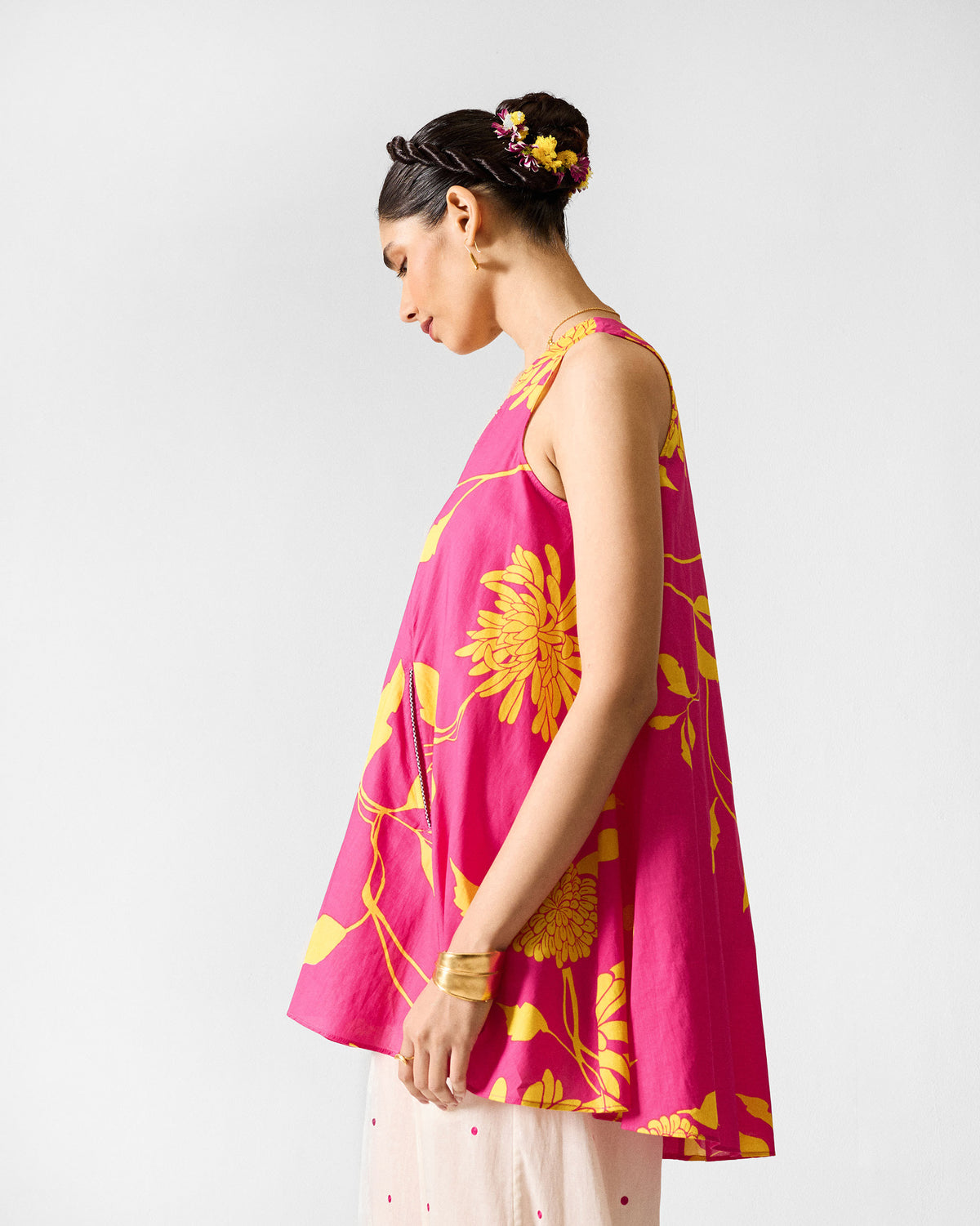Side view of a fuchsia lantern top with yellow floral print showing its flared shape.