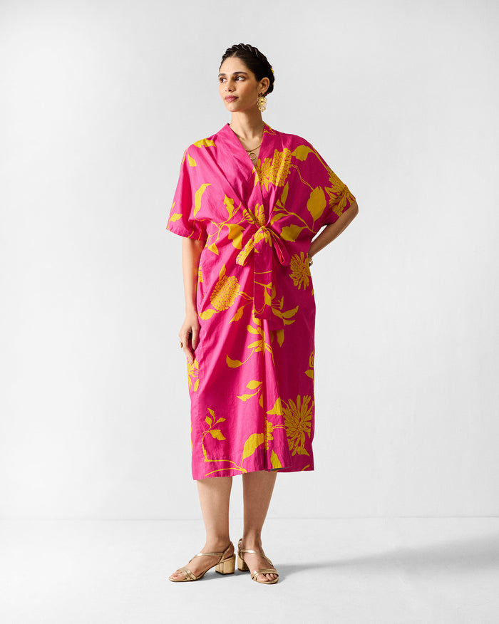 Person wearing a fuchsia Doda dress with lime floral print and waist tie.
