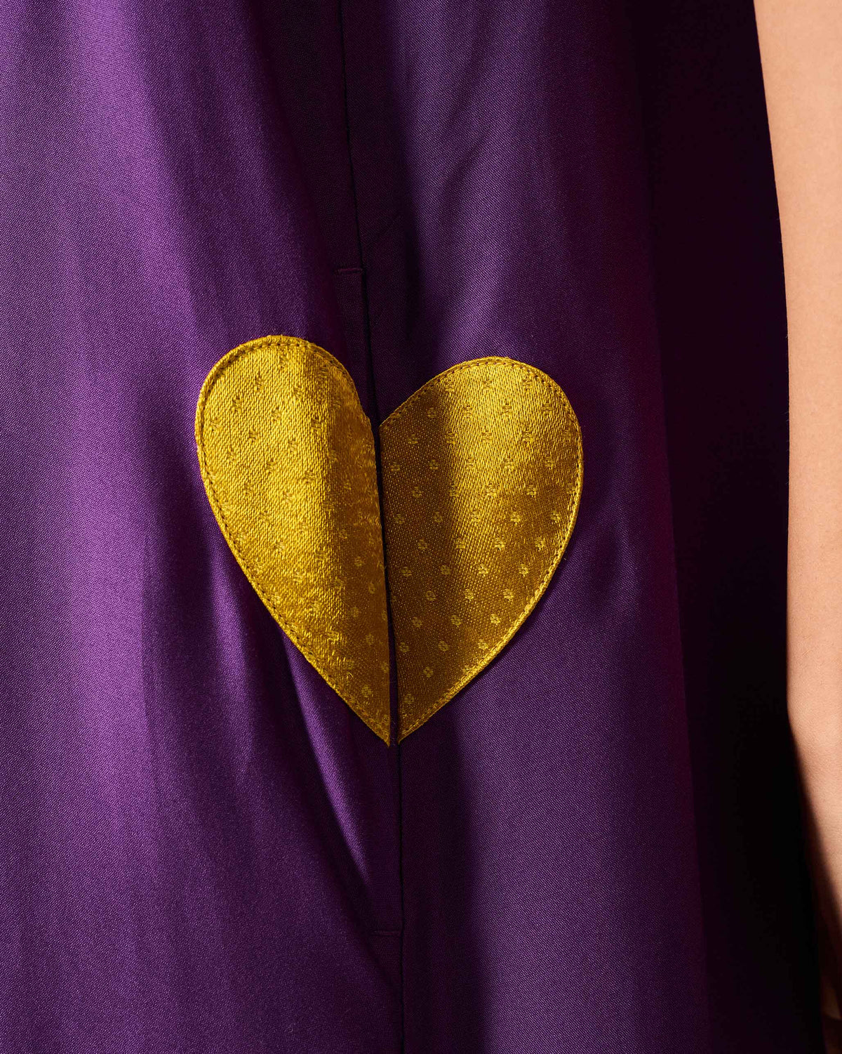 Close-up of a yellow heart on the pocket of a purple Amreli jumpsuit.