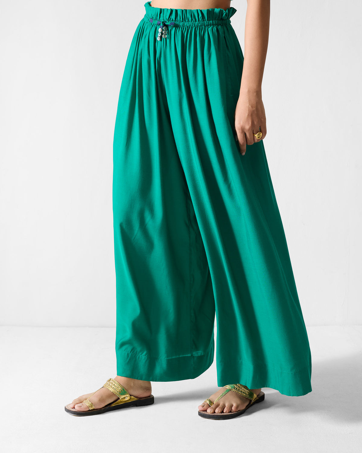 Three-quarter view of green paperbag pants with a gathered waist and wide legs.
