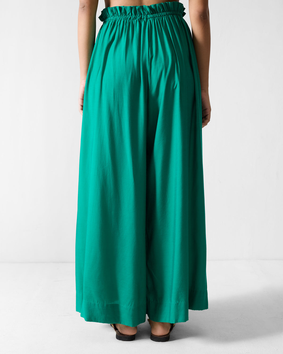 Back of green paperbag pants with a gathered waist worn by a person.