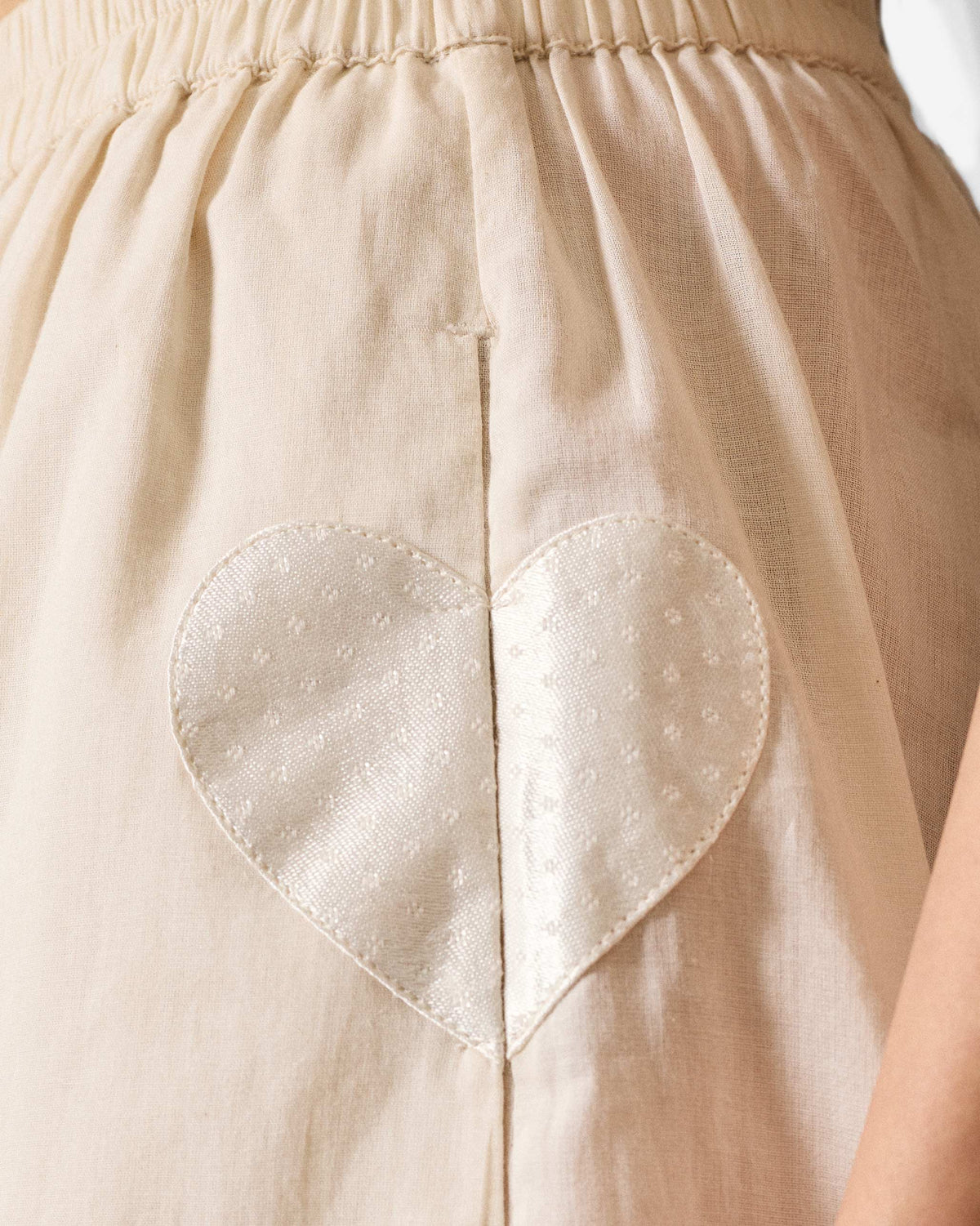 Close-up of ivory Jaisalmer Pants waist with a white heart applique.