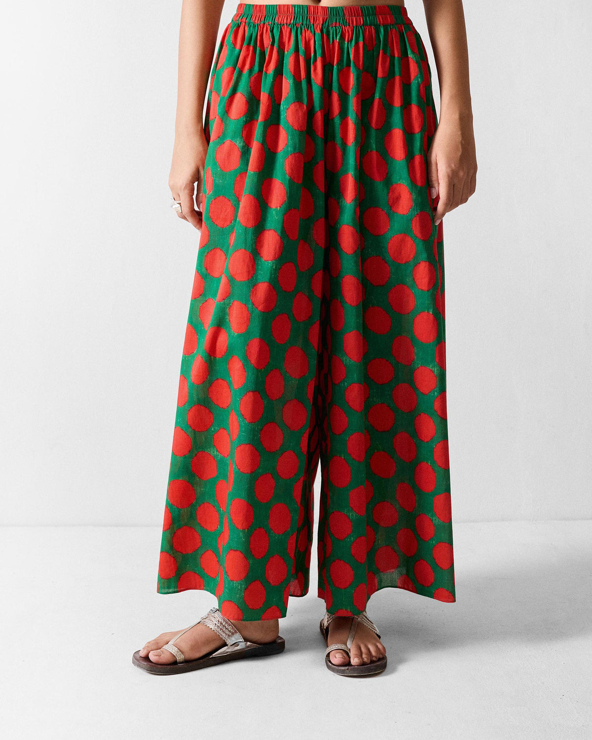 Person wearing Yoi Hem Pants in green with a bold red dot print.