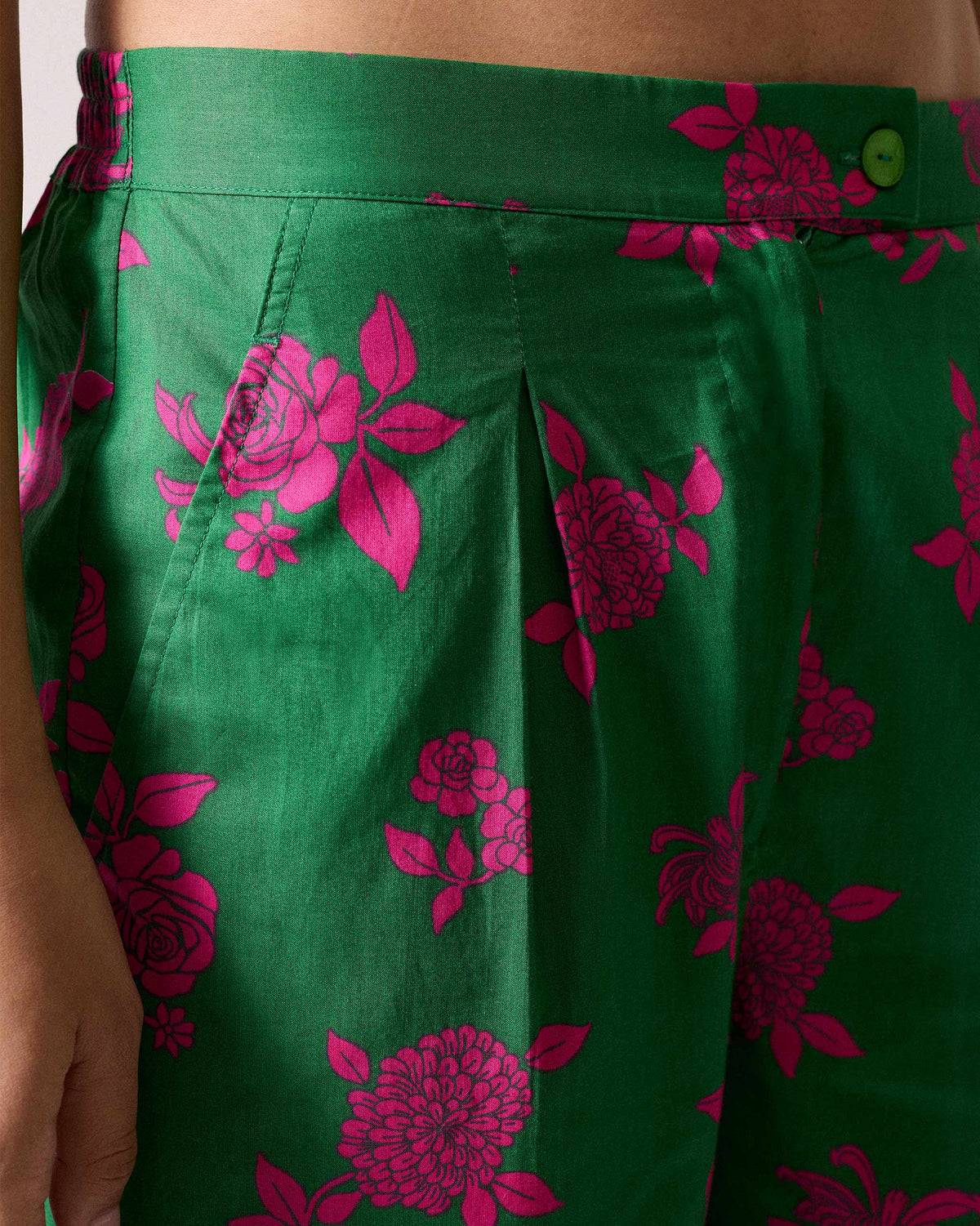Close-up of the waistband and pink floral print on green Novel narrow pants.