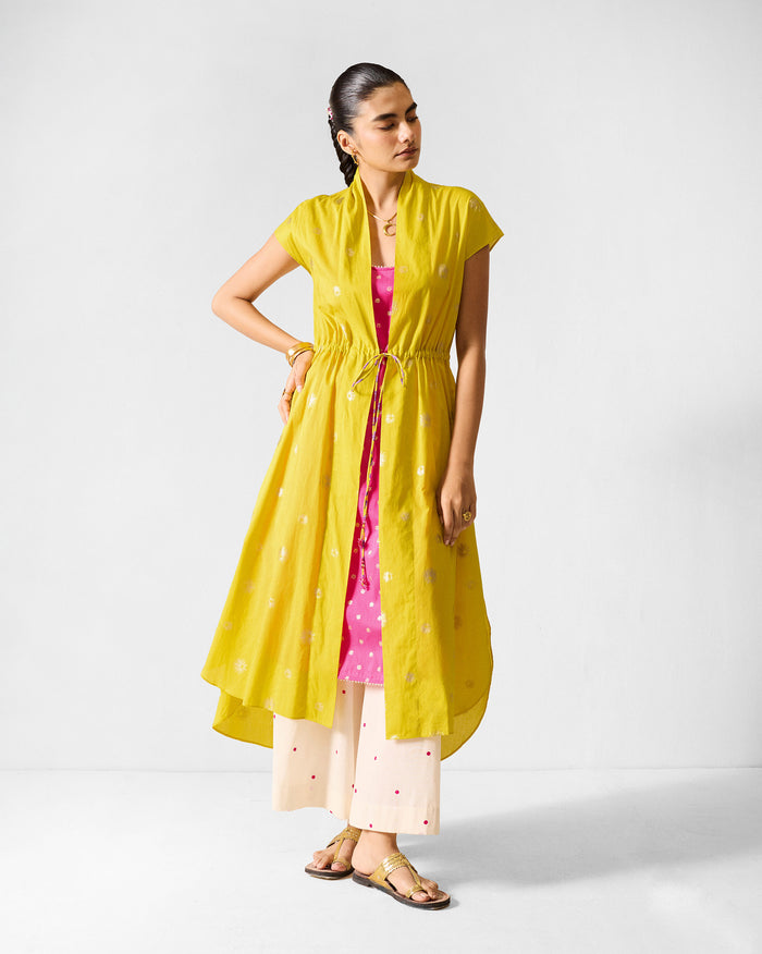 Person wearing a chartreuse Myra overlay with gold print and a drawstring waist.