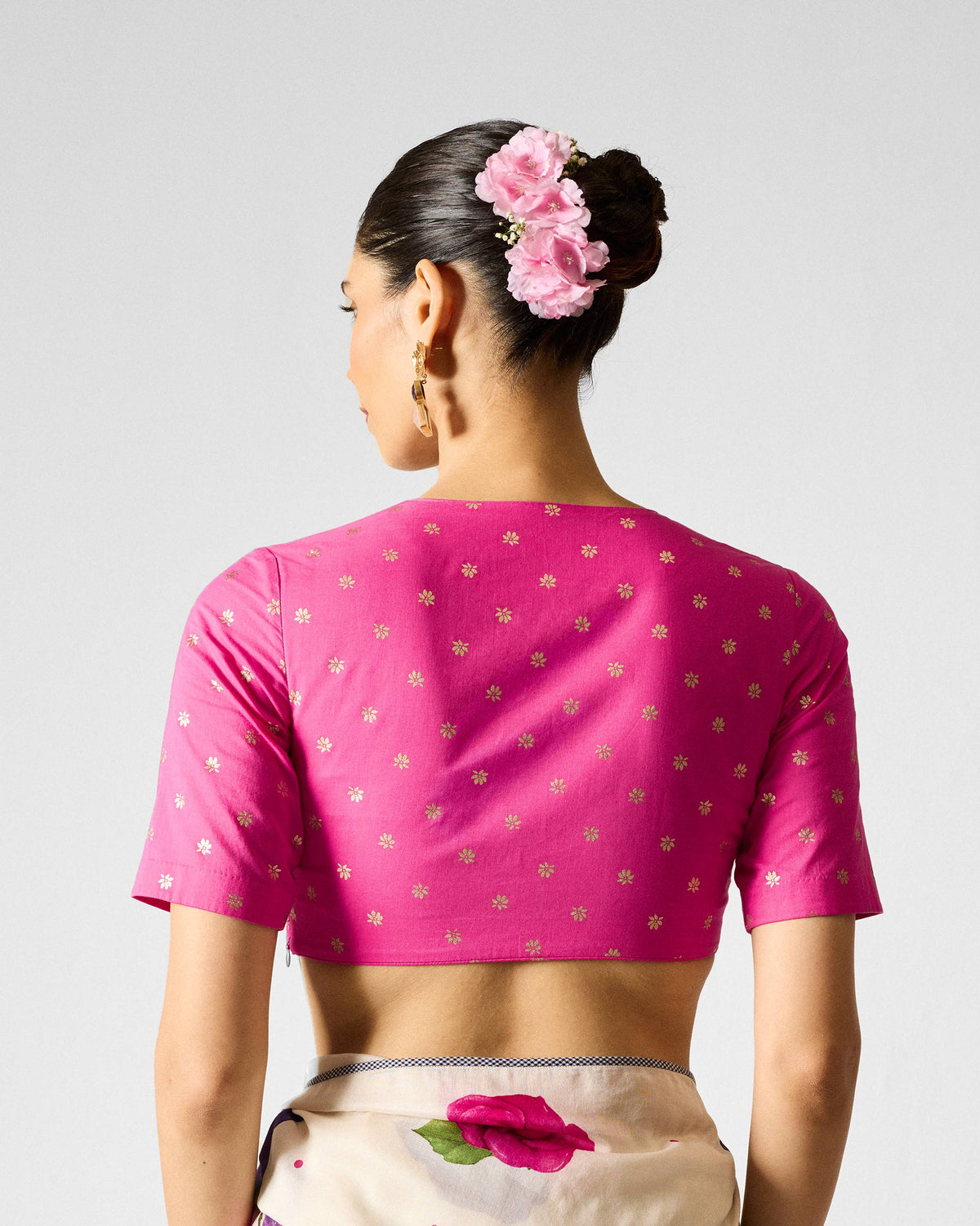 Back of fuchsia Ira Blouse with gold printed flowers worn by a person.