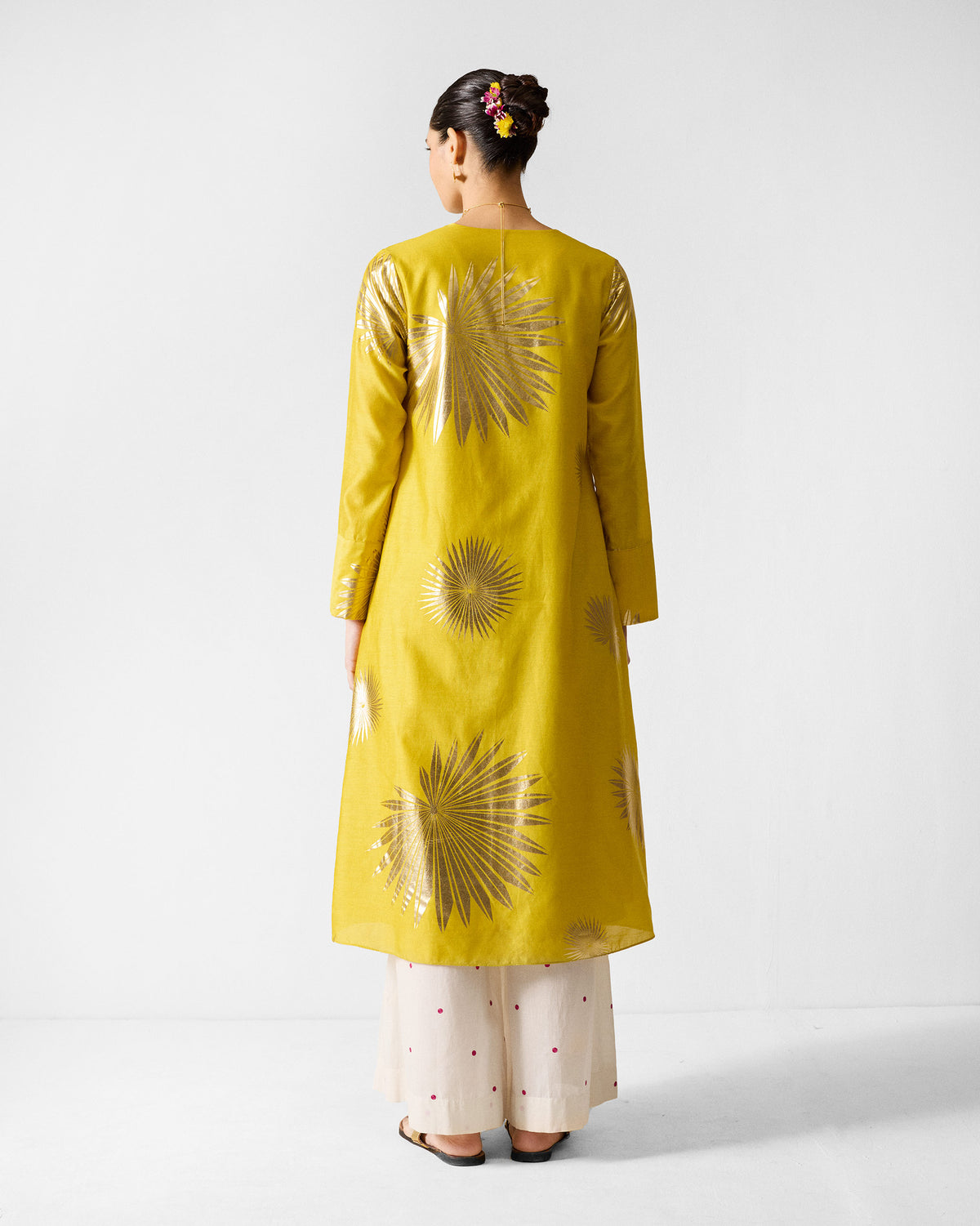 Back of a chartreuse gold-printed kurta with palm and sunburst motifs.