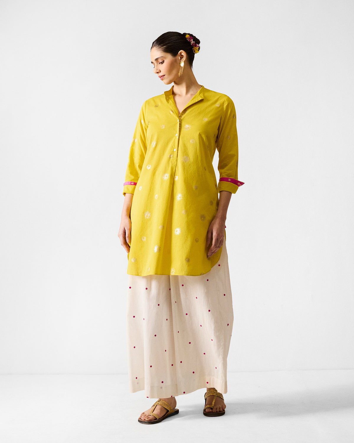 Person wearing a chartreuse and gold printed mid length kurta with pink cuff trim.