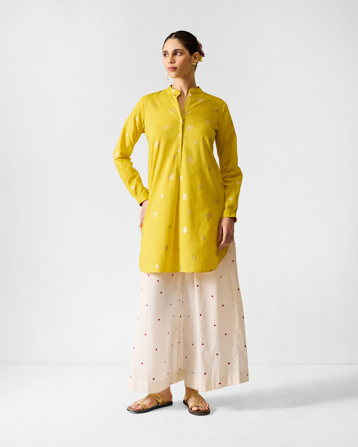 Person wearing a chartreuse mid-length kurta with scattered gold motifs.