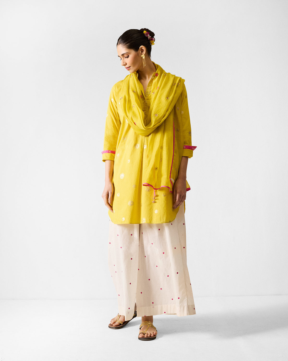 Person wearing a chartreuse kurta with a matching yellow scarf and pink trim.
