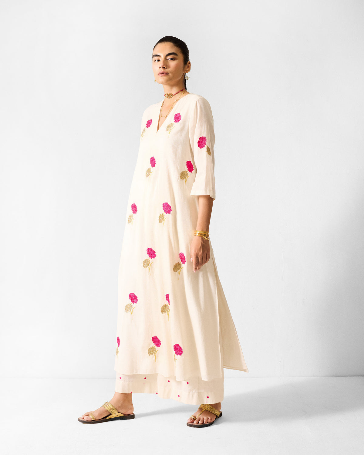 Person wearing an ivory Hampi Kurta with fuchsia marigold embroidery.