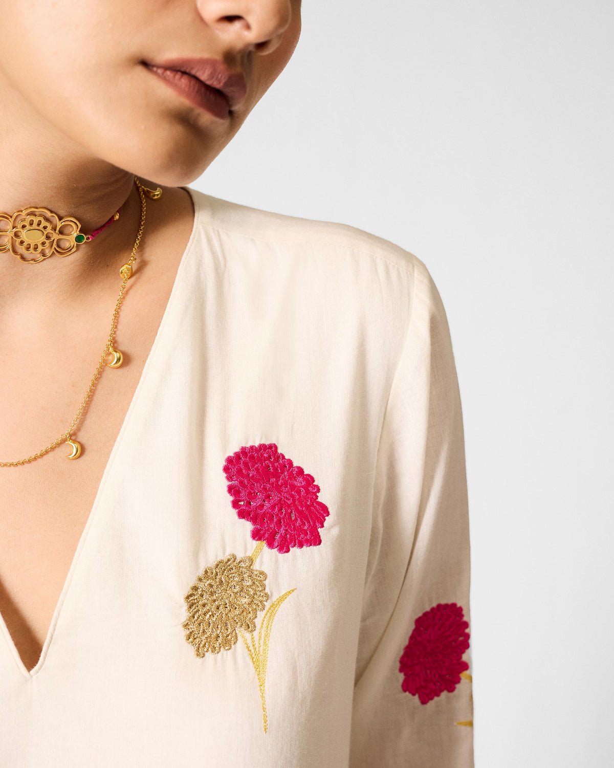 Close-up of an ivory Hampi Kurta showing fuchsia and gold floral embroidery.