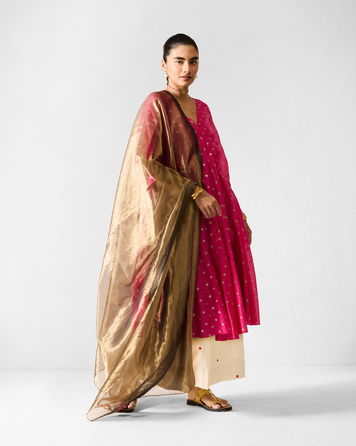Person wearing a fuchsia Kannauj Kurta with a metallic gold dupatta.