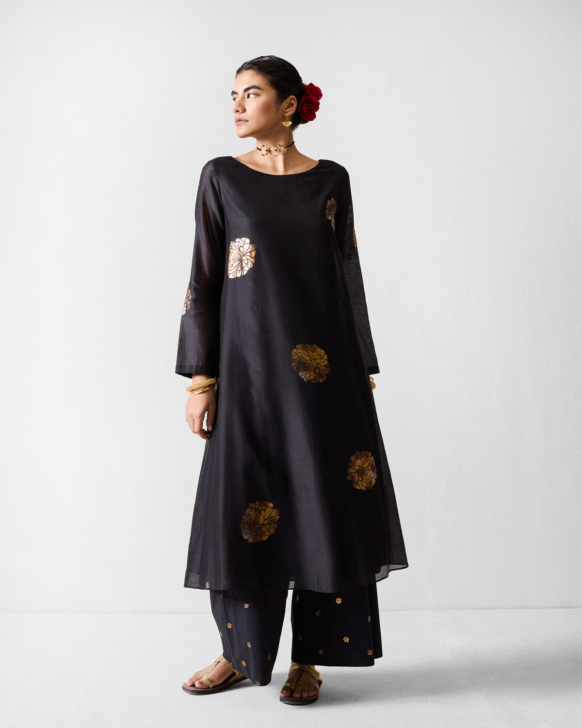 Person wearing a black and gold printed boat neck kurta with floral motifs.