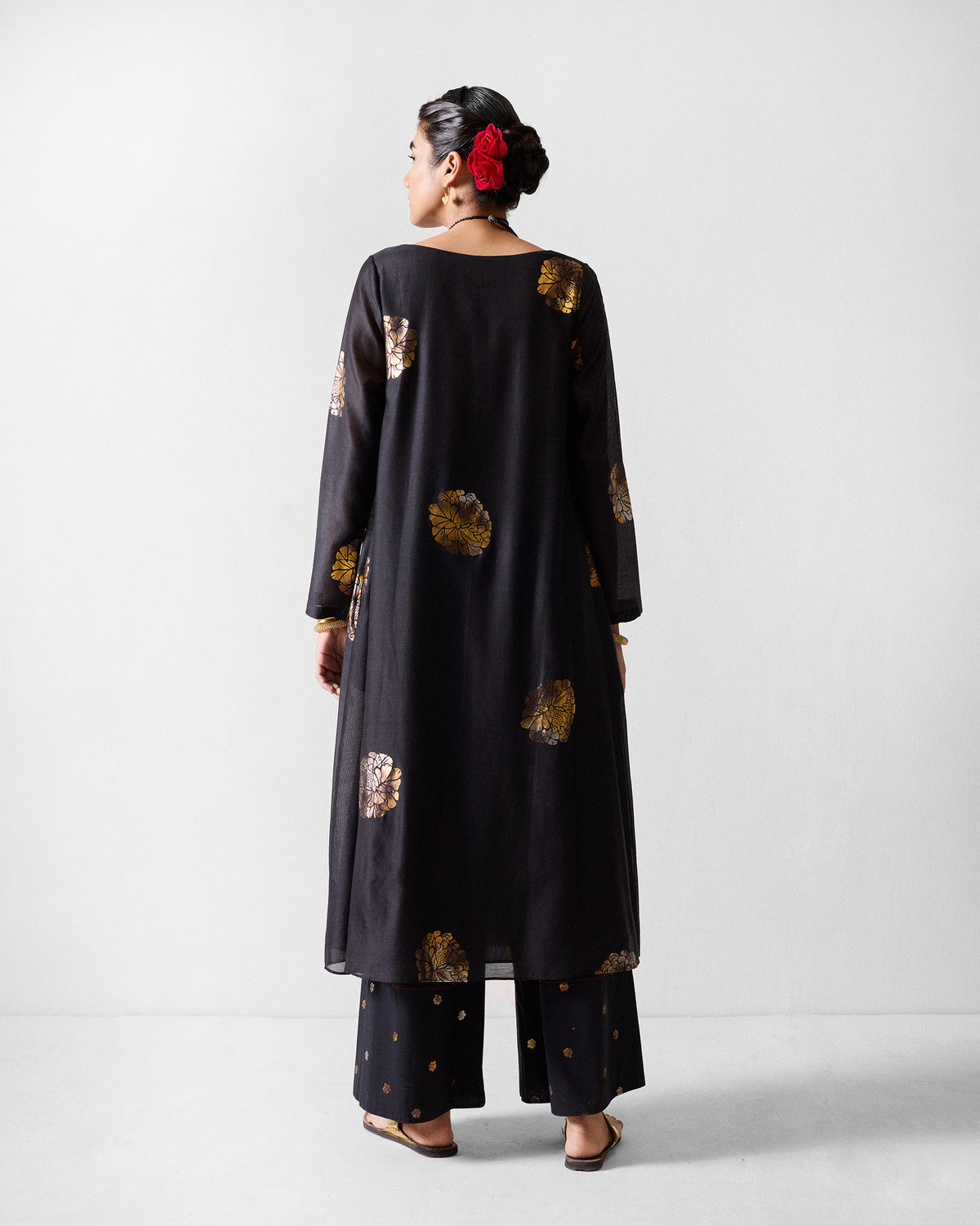 Back of a black boat-neck kurta with scattered gold foil motifs.