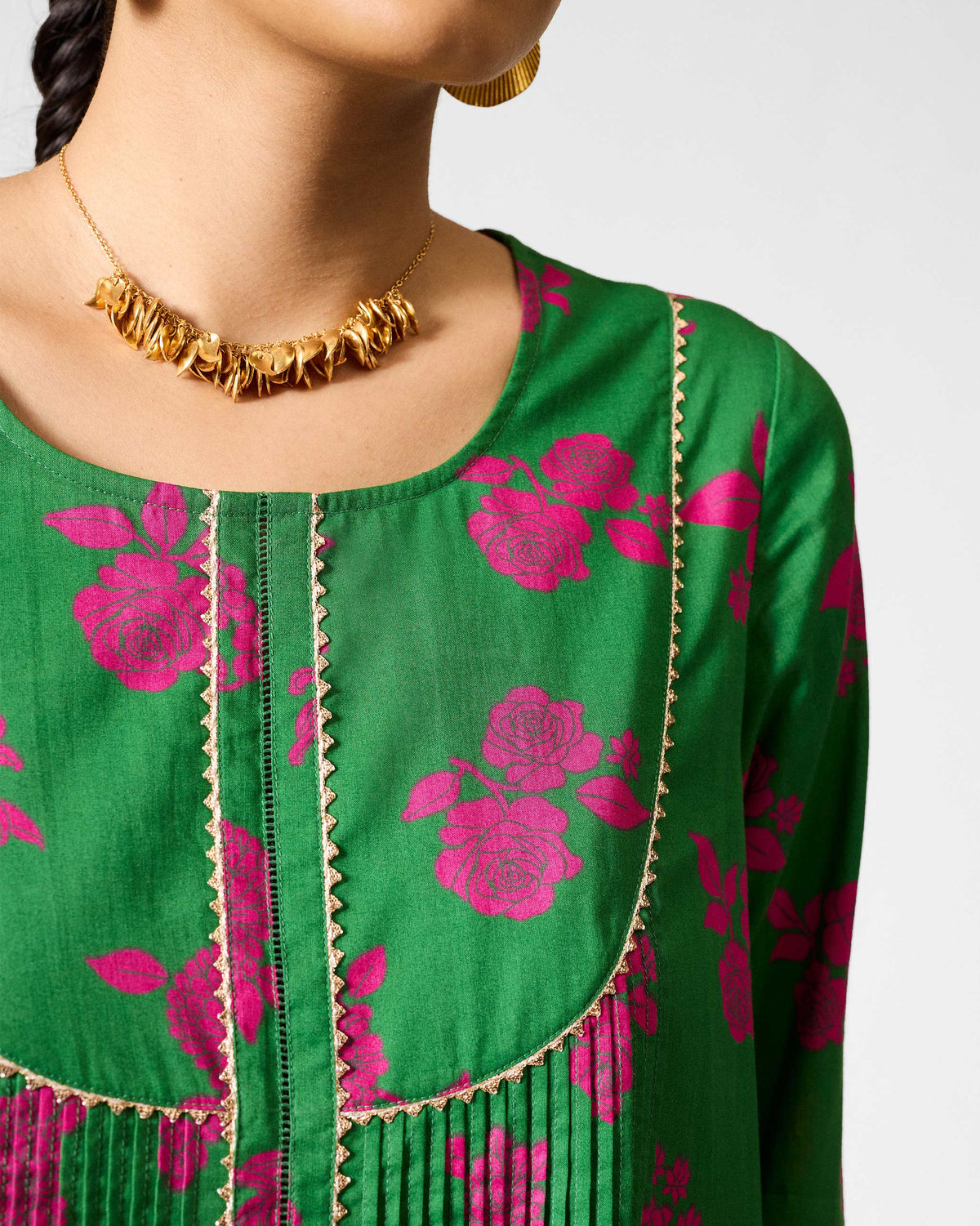 Close-up of gold scalloped trim and fuchsia roses on a green Ayat kurta.